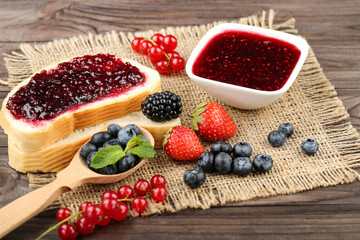 Poster - Toast with jam in bowl and fresh berries on wooden table