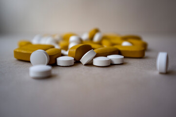 Nutrition supplement pills, white and yellow medicine pills on grey and brown background, vitamin pills