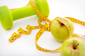 dumbbell,  green apples, yellow measuring tape on a white background top view