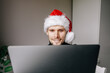 © Girts - Portrait of smiling handsome man in his home office. Working from home businessman wearing red Santa hat  Adult entrepreneur looking at camera sitting at his desk. Close up portrait.