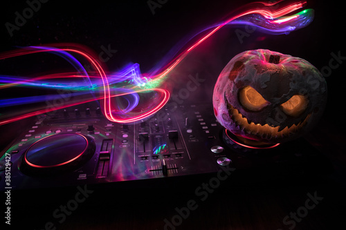 Halloween pumpkin on a dj table with headphones on dark background with copy space. Happy Halloween festival decorations