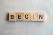 The word begin written on square wooden blocks. Black letters on wood tiles with a white background 