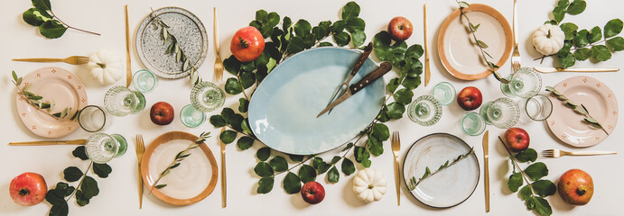 Wall Mural - Autumn Thanksgiving, Friendsgiving, family gathering dinner table setting. Flat-lay of Fall table with tableware and cutlery decorated with pumpkins, fruits and leaves over plain white background