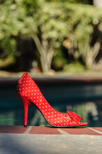 Red High Heel Shoe - Right Side Profile Beside Swimming Pool.