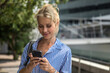 © Jovo Jovanovic/Stocksy - Attractive blonde woman using phone outdoors