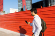 © VITTA GALLERY/Westend61 - Male entrepreneur using mobile phone while walking by wall in city