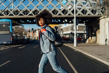Young Woman With Afro Hair Walking On Street During Sunny Day