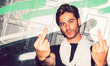 © EDUARDOHUELINPHOTO/Westend61 - Close-up of handsome man showing middle fingers against graffiti wall at night