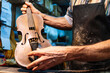 © Jose Luis CARRASCOSA/Westend61 - Violin maker examining violin for repairing at workshop