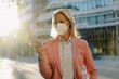 © Joseffson/Westend61 - Businesswoman wearing face mask while using smart phone in financial district during pandemic