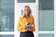 © Robijn Page/Westend61 - Confident female entrepreneur holding digital tablet while standing against wall in home office