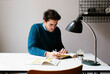 © Sofie Delauw/Westend61 - Male architect reading book while sitting at desk in office