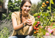 © UWE_UMSTAETTER/Westend61 - Happy beautiful woman picking cherry tomatoes in vegetable garden