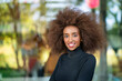 © dirk moll fotografie/Westend61 - Close-up portrait of smiling businesswoman with curly frizzy hair standing outdoors