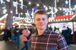 © William Perugini/Westend61 - Close-up of handsome young man standing in illuminated Christmas market