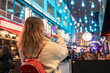 © William Perugini/Westend61 - Young woman photographing illuminated Christmas lights hanging in city at night