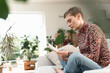 © UWE_UMSTAETTER/Westend61 - Mid adult woman with short hair reading book while sitting on sofa at home