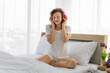 © tuaindeed - Attractive young woman listening music on her bed in morning.