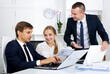 © JackF - Portrait of three smiling business colleagues discussing paper work with document in hands in office. Focus on the left man