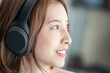 © marchsirawit - Woman listens music wearing and touches over ear headphones.