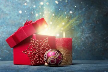 Wall Mural - Magic golden light from red gift box with shiny satin bow, candle and christmas ball