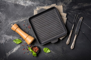 Wall Mural - Grill pan with bright spices, basil leaves, pepper mill and silver cutlery for tasty cooking