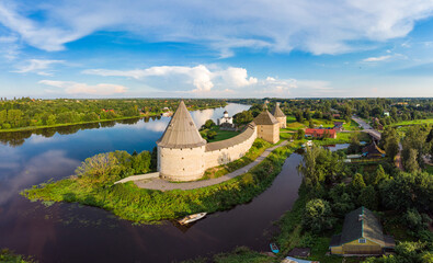 Aerial panoramic view of famous medieval fortress in Staraya Ladoga at sunset. Ancient Russian historical fort on Volkhov River on a sunny summer day. Europe, Russia, Leningrad region, St. Petersburg.