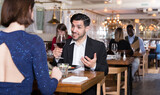 Fototapeta  - Smiling bearded man with female colleague on friendly meeting over dinner in restaurant