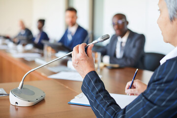 Wall Mural - close-up of mature speaker speaking to microphone for auditorium at conference