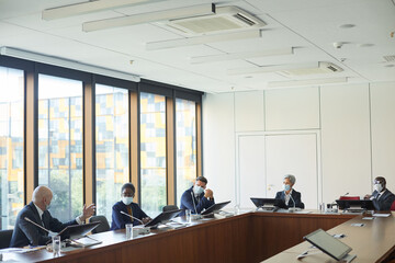 Wall Mural - group of business people in protective masks sitting at the table during conference at board room