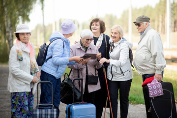 Group of positive senior elderly people looking at digital map on traveling journey during pandemic.COVID-19 travel in the New Normal.