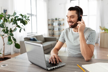 Wall Mural - remote job, technology and people concept - happy smiling man with headset and laptop computer havin