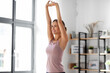 © Syda Productions - sport, fitness and healthy lifestyle concept - smiling young woman stretching arms at home