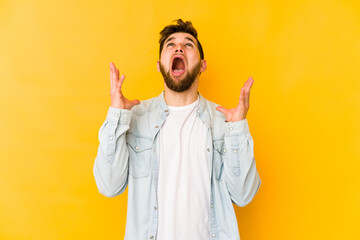 Wall Mural - Young caucasian man isolated on yellow background screaming to the sky, looking up, frustrated.