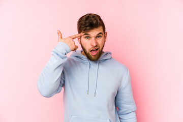 Wall Mural - Young caucasian man isolated on pink background showing a disappointment gesture with forefinger.