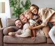 © JenkoAtaman - happy family mother father and kids at home on couch .