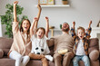 © JenkoAtaman - family of fans watching a football match and celebrating goal on TV at home.