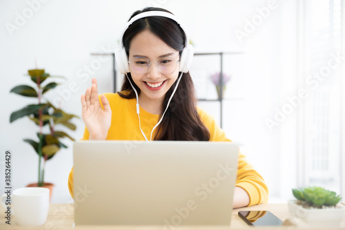 Young asian woman in headphone having conversation chatting while using laptop at house. Work at home, Video conference, Online meeting video call, Virtual meetings, Remote learning and E-learning