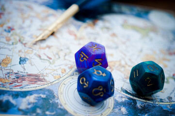 astrological cubes, blue feather quill pen lying on horoscope with zodiac signs like old astrology c