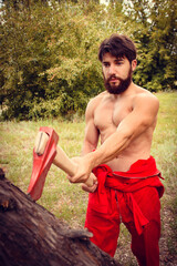 Woodcutter in red coveralls with axe in forest