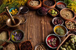 © zolnierek - Natural medicine theme. Assorted dry herbs in bowls and brass mortar on rustic wooden table.