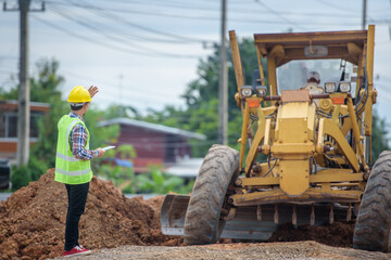 Asian engineers watch road rebuilding and inspect the construction of the road at the construction site.