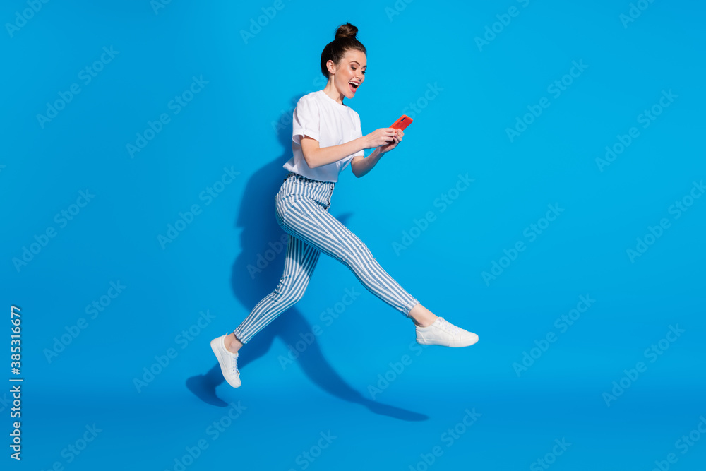 Full length body size view of nice attractive cheerful carefree girl jumping using technology virtual connection wi-fi having fun isolated on bright vivid shine vibrant blue color background - obrazy, fototapety, plakaty 