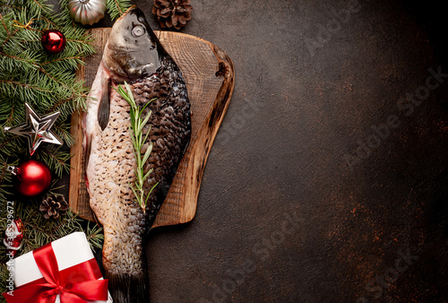raw carp for preparation for the holiday Christmas on a background of stone with Christmas trees and Christmas decorations \
with copy space for your text