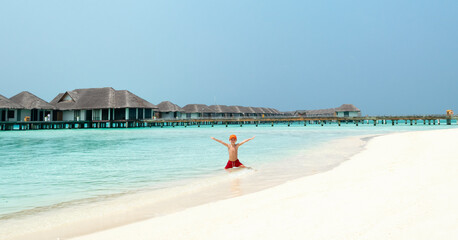 Cheerful kid on tropical beach of Maldives islands.