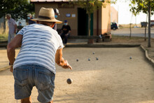 Old Man Wearing A Hat Playing Petanque Outdoors.