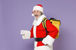 © ViDi Studio - Side view of excited elderly Santa Claus man in Christmas hat red suit coat glasses thermal food bag backpack isolated on violet background studio. Happy New Year celebration merry holiday concept.