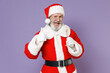 © ViDi Studio - Blinking Santa Claus man in Christmas hat red suit coat gloves glasses hold glass of champagne showing thumb up isolated on violet background studio. Happy New Year celebration merry holiday concept.