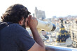 Selective focus shot of an handsome caucasian male admiring Madrid through a telescope
