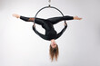 © Kseniia - A female gymnast performing exercises on an air ring (hoop) on a gray background